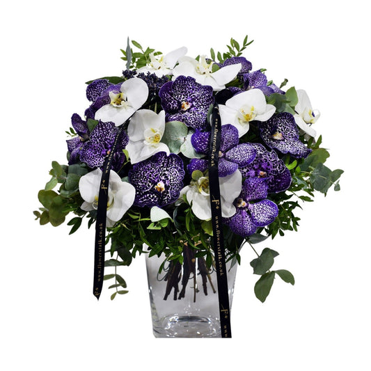 Bouquet of purple and white flowers in a clear vase on a white background