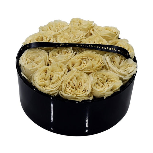 A glass container with preserved cream roses tightly arranged, possibly as a gift for an anniversary or other special occasion.