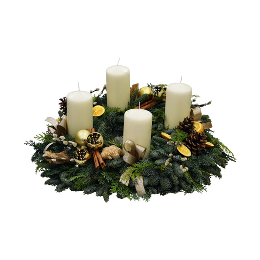 A handcrafted advent wreath with white candles, fresh scented pine, orange slices, and decorations including elegant berries and fruit.