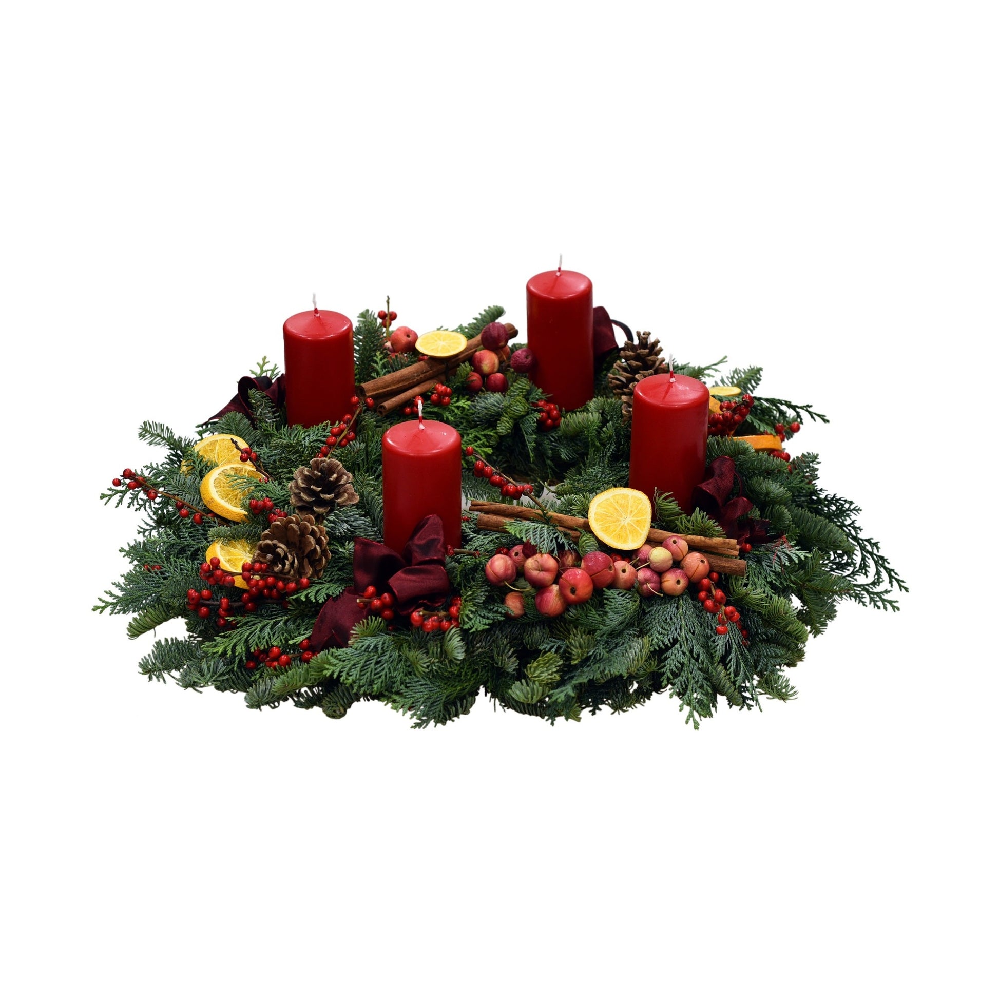 A handcrafted advent wreath with fresh scented pine, red candles, freeze-dried orange slices, and other decorations including berries and fruit.