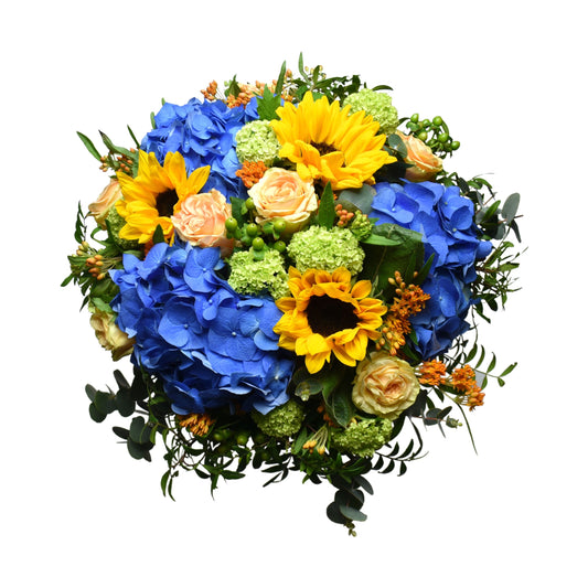 A vibrant summer bouquet with a mix of blue hydrangeas, yellow sunflowers, pink roses, green hypericum, and a variety of foliage.