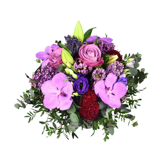 A hand-tied bouquet with a variety of flowers including pink vanda orchid, pink syringe, pink oriental lily, antique pink rose, and blue eustoma, with greenery in the background.